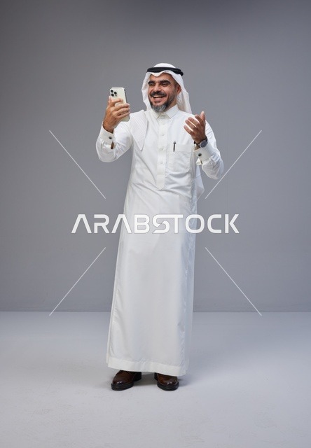 Saudi Man in Traditional Thobe Using Smartphone
