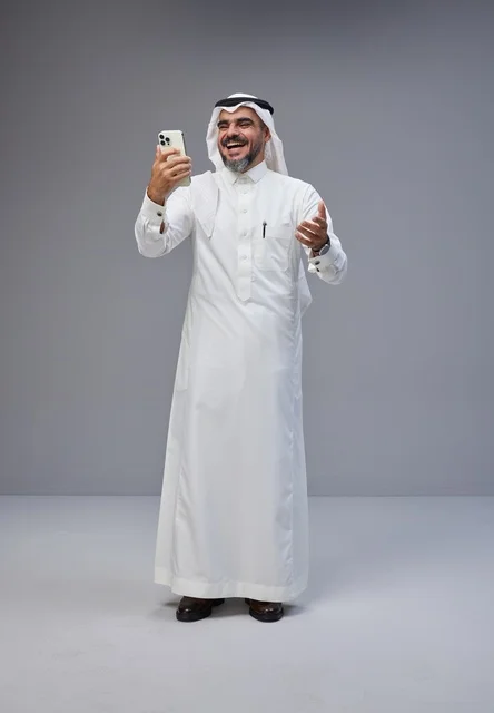 رجل سعودي بالزي التقليدي يستخدم الهاتف الذكي