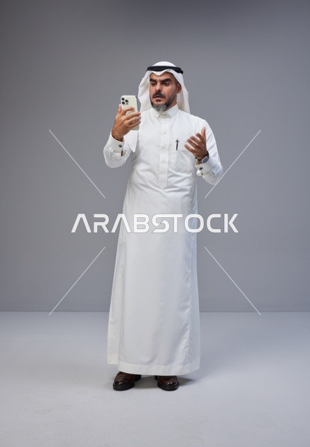 Saudi Man in Traditional Thobe Using Smartphone in Studio