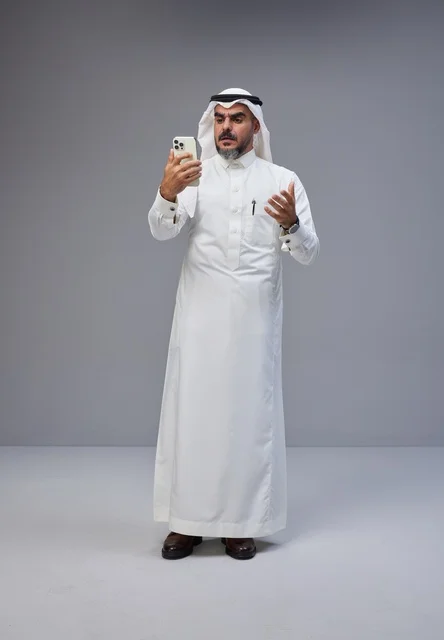 Saudi Man in Traditional Thobe Using Smartphone in Studio