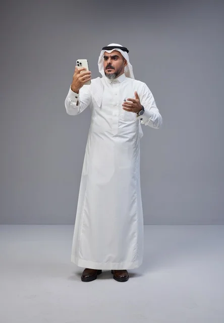 Saudi Man in Traditional Dress Using Smartphone