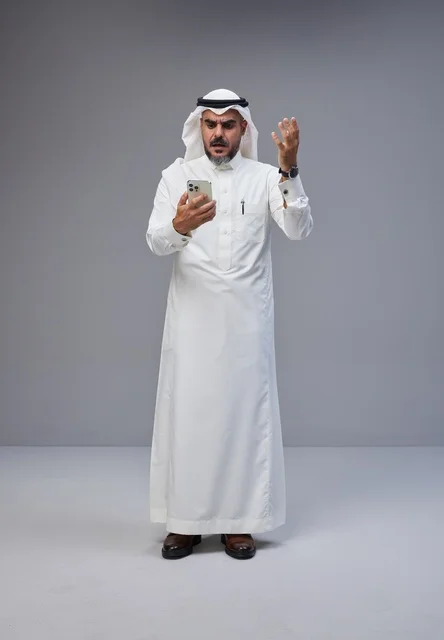 Frustrated Saudi Man in Traditional Thobe Using Smartphone