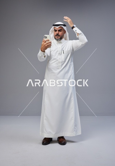 Saudi Man in Traditional Thobe Using Smartphone