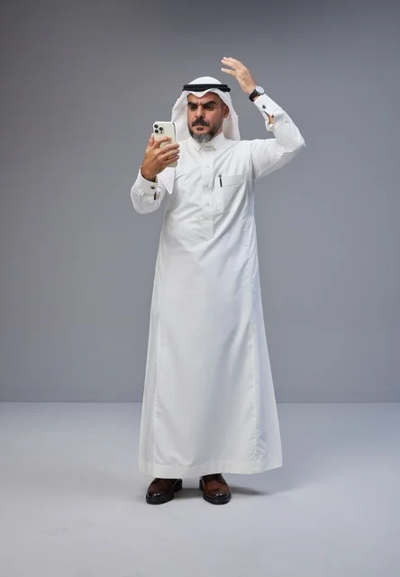 Saudi Man in Traditional Thobe Using Smartphone