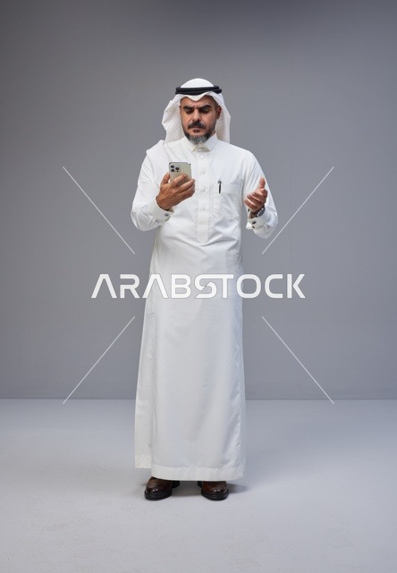Saudi Man in Traditional Thobe Using Smartphone