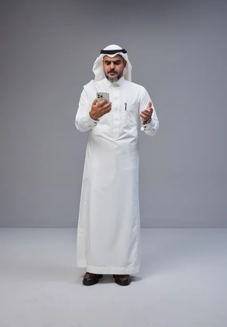 Saudi Man in Traditional Thobe Using Smartphone