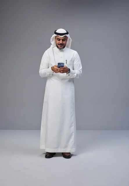 رجل سعودي بالزي التقليدي يستخدم الهاتف الذكي