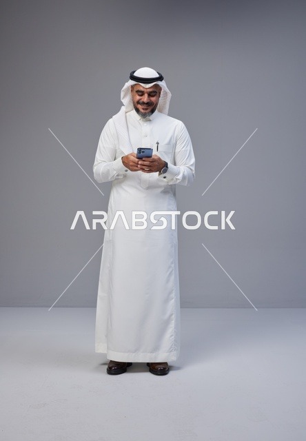 رجل سعودي بالزي التقليدي يستخدم الهاتف الذكي