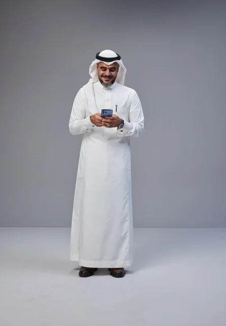 رجل سعودي بالزي التقليدي يستخدم الهاتف الذكي