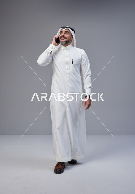 رجل سعودي بالزي التقليدي يتحدث عبر الهاتف المحمول