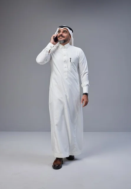 رجل سعودي بالزي التقليدي يتحدث عبر الهاتف المحمول