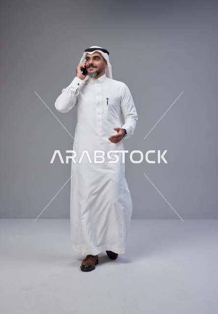رجل سعودي بالزي التقليدي يتحدث عبر الهاتف المحمول
