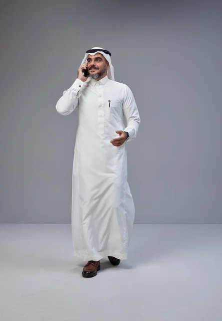 رجل سعودي بالزي التقليدي يتحدث عبر الهاتف المحمول