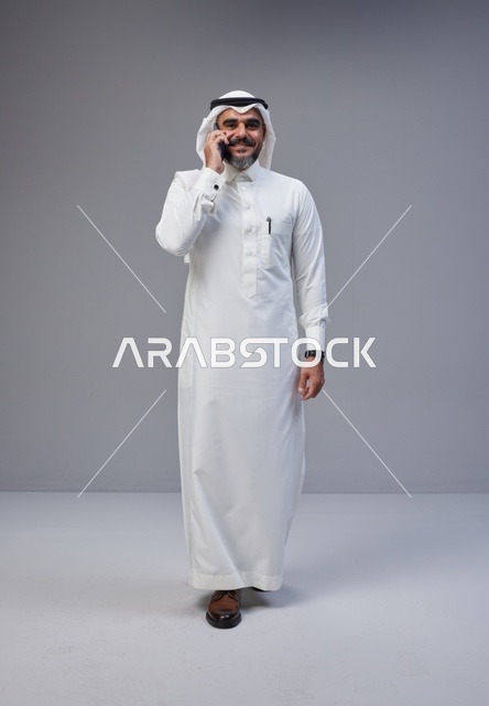 رجل سعودي بالزي التقليدي يتحدث عبر الهاتف الجوال