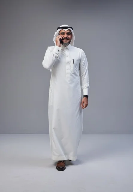 رجل سعودي بالزي التقليدي يتحدث عبر الهاتف الجوال