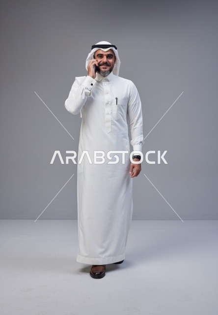 رجل سعودي بالزي التقليدي يتحدث عبر الهاتف الجوال