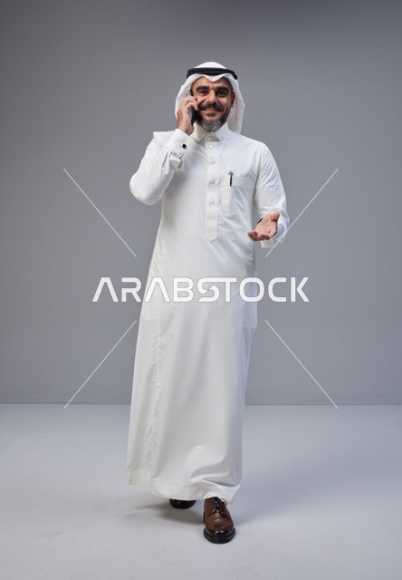 Saudi Man in Traditional Thobe Talking on Smartphone