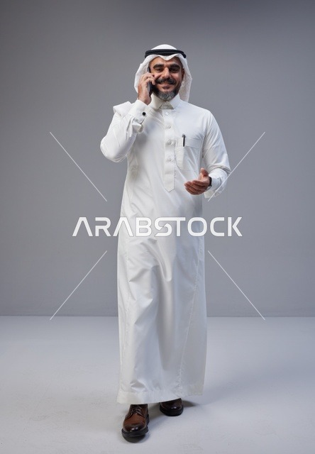 رجل سعودي بالزي التقليدي يتحدث عبر الهاتف الذكي