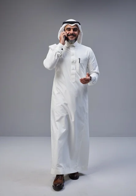 Saudi Man in Traditional Thobe Talking on Smartphone