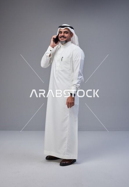 رجل سعودي بالزي التقليدي يتحدث عبر الهاتف الذكي