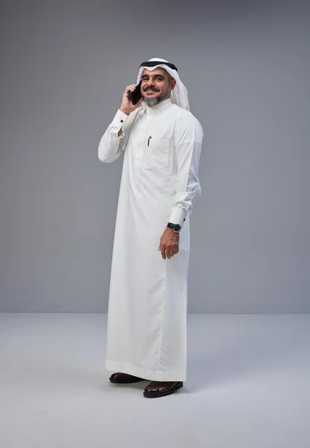 Saudi Man in Traditional Thobe Talking on Smartphone