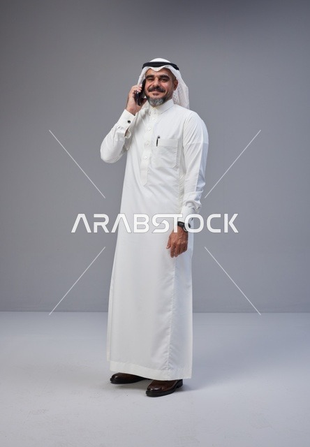رجل سعودي بالزي التقليدي يتحدث عبر الهاتف مع إيماءة تعبيرية