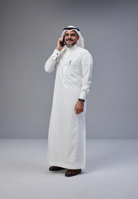 Saudi man in traditional attire talking on phone with expressive gesture