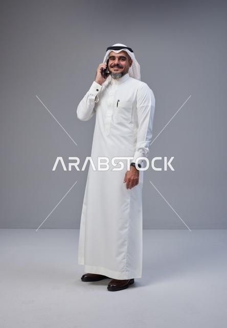 رجل سعودي بالزي التقليدي يتحدث عبر الهاتف المحمول