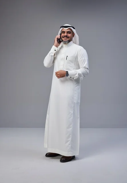 رجل سعودي بالزي التقليدي يتحدث عبر الهاتف الذكي