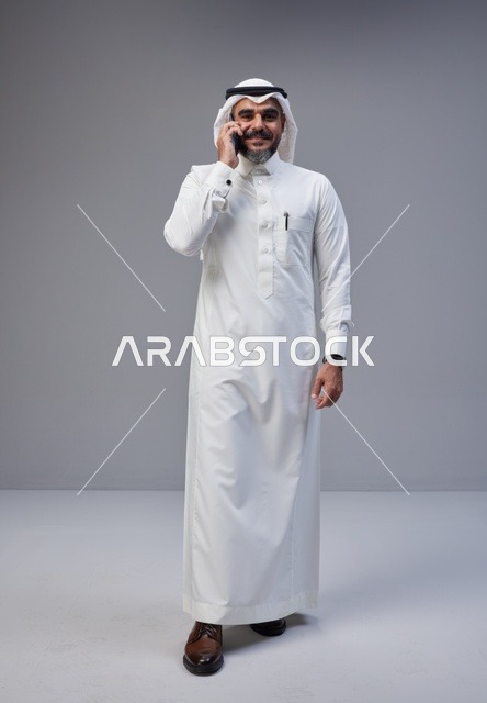 Saudi Man in Traditional Thobe Talking on Smartphone