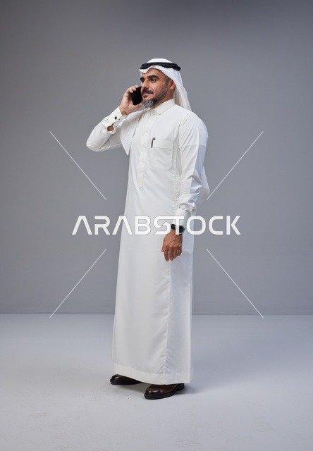 Saudi Man in Traditional Thobe Talking on Phone