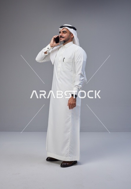 Saudi Man in Traditional Thobe Talking on Smartphone