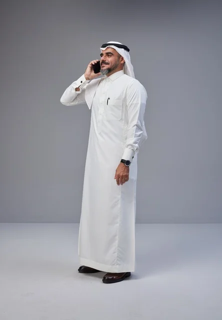 Saudi Man in Traditional Thobe Talking on Smartphone
