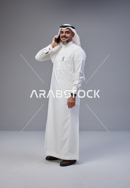 رجل سعودي بالزي التقليدي يتحدث عبر الهاتف الجوال