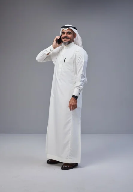 Saudi Man in Traditional Thobe Talking on Smartphone
