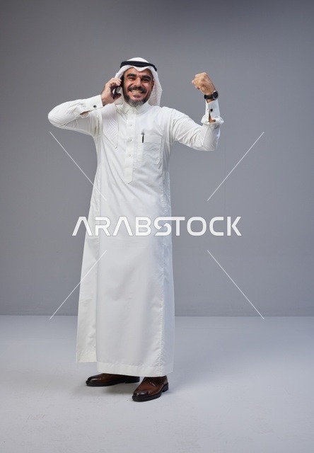 رجل سعودي بالزي التقليدي يحتفل بنجاح عبر الهاتف
