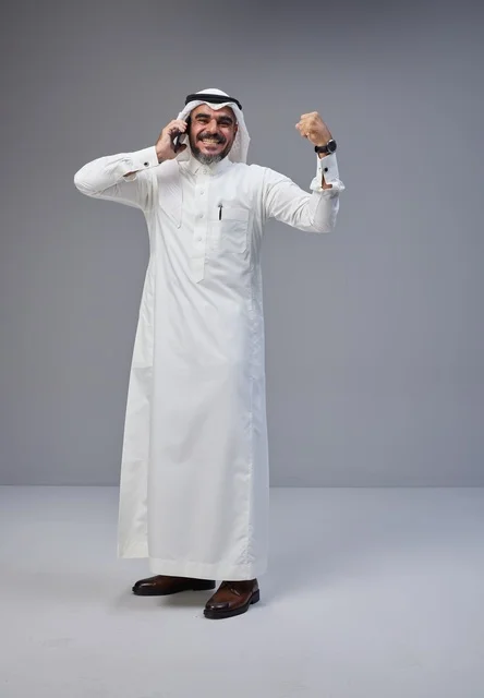 رجل سعودي بالزي التقليدي يحتفل بنجاح عبر الهاتف