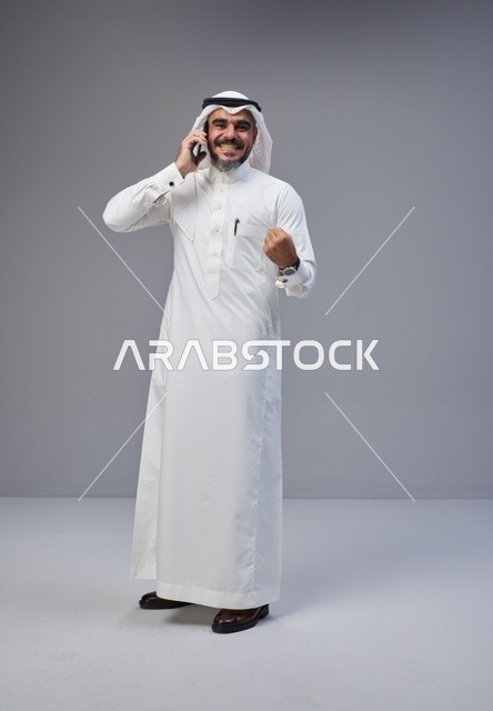 Saudi Man Talking on Smartphone with Success Gesture