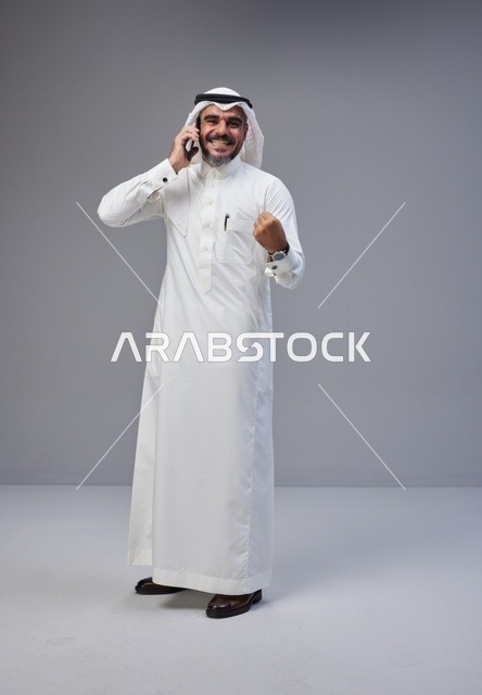 رجل سعودي يتحدث بالهاتف مع إيماءة نجاح