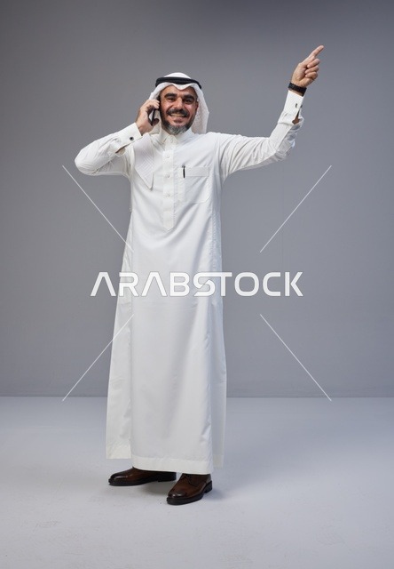 Saudi Man in Thobe Talking on Phone Pointing Upwards