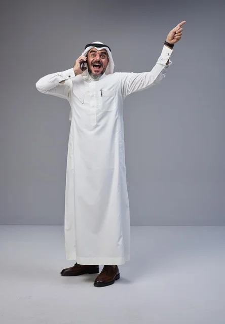 رجل سعودي بالزي التقليدي يتحدث بالهاتف ويشير للأعلى