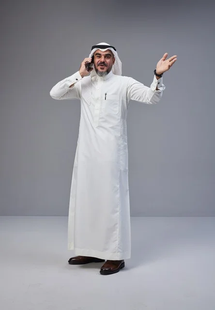 Saudi Man in Traditional Thobe Talking on Smartphone