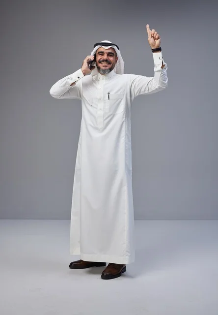 Saudi man in traditional attire talking on phone with expressive gesture