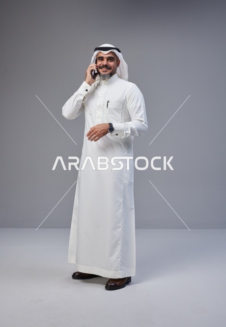 رجل سعودي بالزي التقليدي يتحدث عبر الهاتف المحمول