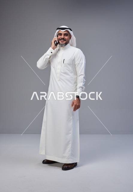 رجل سعودي بالزي التقليدي يتحدث عبر الهاتف الذكي