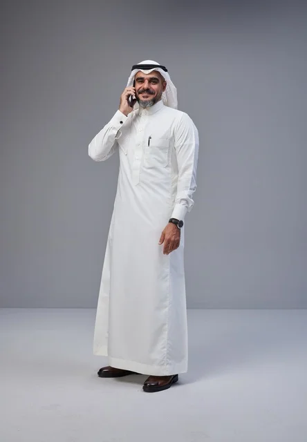 Saudi Man in Traditional Thobe Using Smartphone Studio