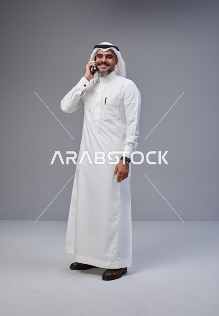 رجل سعودي بالزي التقليدي يتحدث عبر الهاتف الجوال في استوديو