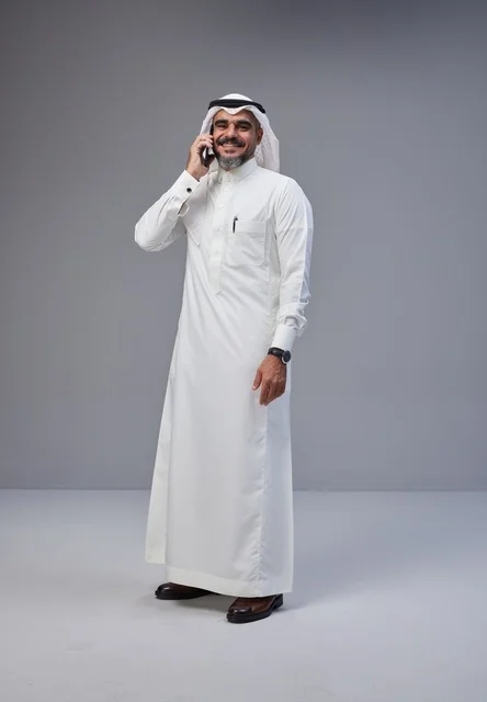 Saudi Man in Traditional Thobe Talking on Smartphone