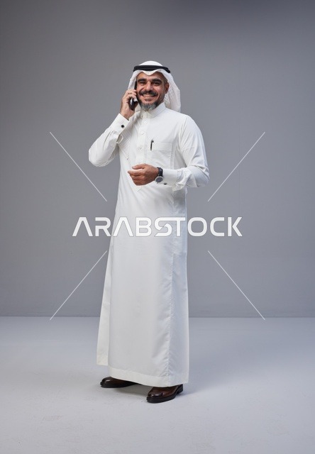 رجل سعودي بالزي التقليدي يتحدث عبر الهاتف المحمول