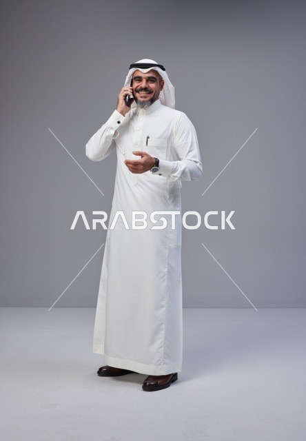 Saudi Man in Traditional Thobe Talking on Smartphone